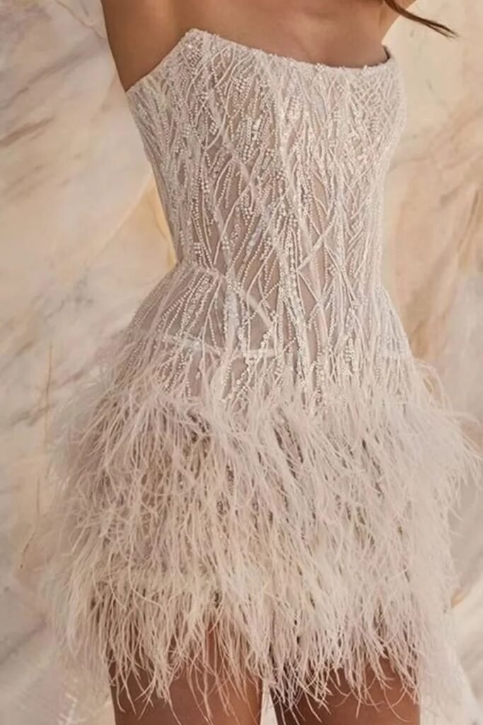 Glamorous sparkling finish Elegant strapless neckline Stylish feathered detailing Contemporary short mini silhouette Ideal for wedding receptions Suitable for bridal celebrations and parties Easy to accessorise with heels and jewellery Modern alternative to a traditional bridal gown